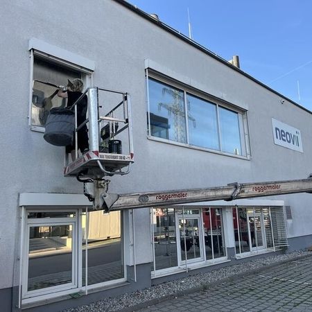 Ein Mitarbeiter foliert eine Fensterscheibe eines Gebäudes
